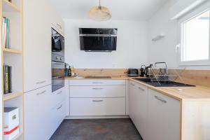 a white kitchen with white cabinets and a sink at Maisonnette Stella Plage Terrasse WIFI in Cucq +9 photos