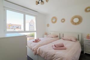 two beds in a room with pink towels on them at Maisonnette Stella Plage Terrasse WIFI in Cucq
