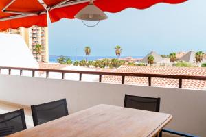 a table and chairs on a balcony with an umbrella at Fabulous two bedroom apartment near las Vistas Beach in Los Cristianos in Arona
