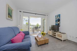 een woonkamer met een blauwe bank en een tv bij Apartamento Carabela 51 in Port d'Alcudia