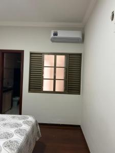 a white room with a bed and a window at Casa Completa à 100m do Parque de Exposição in Patos de Minas