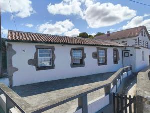 a white building with windows and a wooden fence at Casa dos meus avós Mar & Biscoitos in Biscoitos