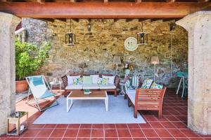 Un patio con sofás y sillas y un reloj en una pared de piedra. en La casa de los Barbazanes, en Brión