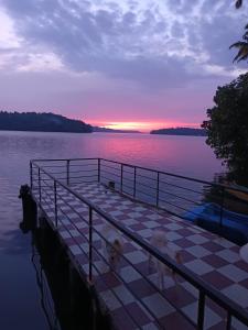 un muelle sobre un cuerpo de agua con puesta de sol en Lake View Homestay Kundara, 