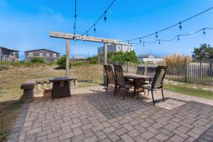 a patio with a table and chairs and a bench at 4018 - Shorely Bliss in Kitty Hawk