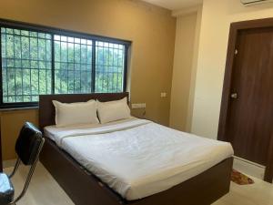 a bedroom with a large bed with white sheets at Gokul Vian Hotels in kolkata