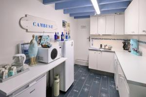 a kitchen with white cabinets and a microwave at La Maison au-dessus des Voiles in La Baule