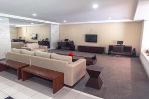 a living room with couches and a flat screen tv at Iguatemi Business by Avectur in Salvador