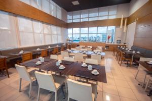 a dining room with tables and chairs and large windows at Iguatemi Business by Avectur in Salvador
