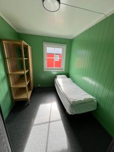 a green room with a bed and a window at Martini Fishing Camp in Lauvsnes