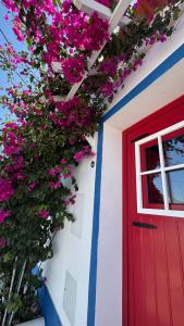 a red door and flowers on a white building at Casa Vó Briata in Mértola