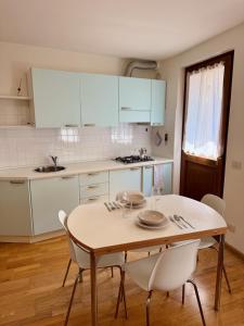 una cucina con un tavolo in legno e mobili bianchi di Accogliente Appartamento nel Centro Storico di Belluno, dietro Piazza delle Erbe a Belluno Altre 32 foto