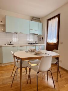 una cucina con un tavolo di legno e sedie bianche di Accogliente Appartamento nel Centro Storico di Belluno, dietro Piazza delle Erbe a Belluno