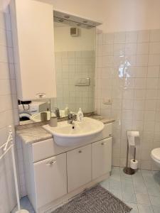 un bagno bianco con lavandino e specchio di Accogliente Appartamento nel Centro Storico di Belluno, dietro Piazza delle Erbe a Belluno