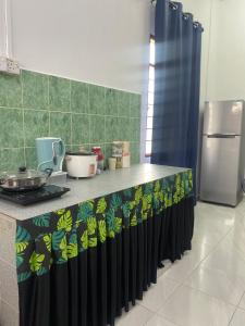 a kitchen with a counter with a stove and a refrigerator at Obah Homestay Kota Bharu in Kota Bharu