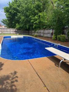 een blauw zwembad met een bankje ernaast bij Spacious, State Line, Private Pool with king Beds in Olive Branch +8 foto's