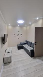 ein Wohnzimmer mit einer Couch und einer Uhr an der Wand in der Unterkunft 1 комн квартира в Кадоре на Таирова in Odessa