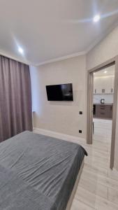 ein Schlafzimmer mit einem Bett und einem Flachbildfernseher in der Unterkunft 1 комн квартира в Кадоре на Таирова in Odessa