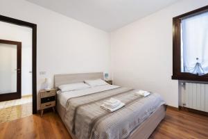 a white bedroom with a bed and a window at Gardoncino apartment with pool in Gardone Riviera +10 photos