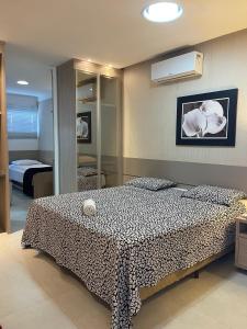 um quarto com uma cama com um cobertor preto e branco em Requinte Flats Beach em Cabo Frio