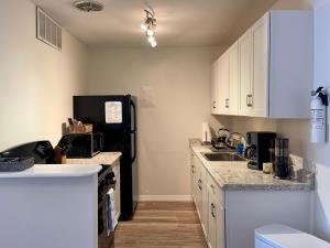 a kitchen with white cabinets and a black refrigerator at Shortest Walk to Shands and UF Health - Quiet, Equipped, Reliable - Free Parking in Gainesville