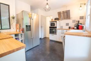 a kitchen with a stainless steel refrigerator and white cabinets at Séjour haut en couleurs in Cormery