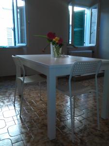 un tavolo bianco con due sedie e un vaso con fiori di Appartamento Federica a Senigallia