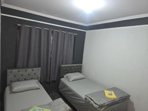 a small room with two beds and a window at Pousada Lotus in Franca