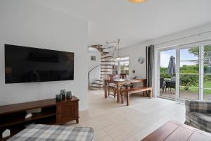 BrösumにあるLille Dröm Reetdachhaus Lille Drömの壁に薄型テレビが取り付けられたリビングルーム