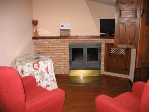 sala de estar con chimenea y sillas rojas en Hotel de Montaña Cueva Ahumada, en Villaverde de Guadalimar