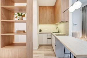 eine Küche mit weißen Arbeitsplatten und Holzschränken in der Unterkunft Domillion Studio Modern Old Town Retreat So1b in Vilnius