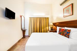 a bedroom with a white bed and a television at FabHotel The Dayal - 24 kms from Delhi Gate, 5 kms from Agra Fort in Agra