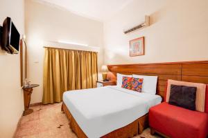 a bedroom with a white bed and a red chair at FabHotel The Dayal - 24 kms from Delhi Gate, 5 kms from Agra Fort in Agra