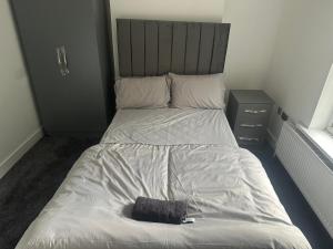 Una cama con una almohada negra encima. en Luton Room only, en Luton