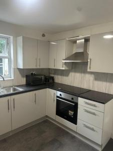 cocina con armarios blancos y fogones negros en Luton Room only, en Luton
