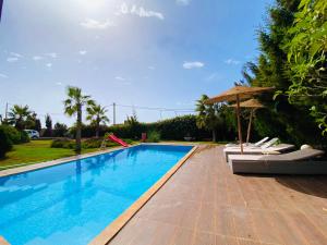 a swimming pool with chairs and an umbrella at Room 1 villa sunset Bouzerktoun in Essaouira