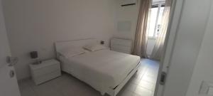 a white bedroom with a white bed and a window at Alessandro's Home in Rome