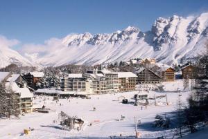 a ski resort with snow covered mountains in the background at Studio Terrasse Le petit cabanon in Serres