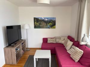 a living room with a purple couch and a tv at Stern Apartments Fontanella in Fontanella