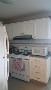 a white kitchen with a stove and a microwave at Chipipe Riviera del Mar in Salinas +8 photos