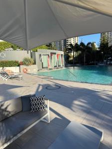 a couch under an umbrella next to a swimming pool at Coastal Dreamscape in Gold Coast