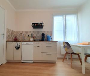 a kitchen with white cabinets and a table and a chair at Apartment in Passage on GR34 in Concarneau