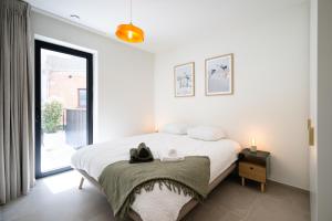 a white bedroom with a bed and a window at Madame Sardine in Ostend