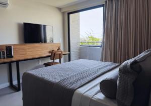a bedroom with a bed and a desk with a television at Nord Class Rio 83 in João Pessoa