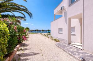 una pasarela junto a un edificio blanco con flores rosas en White Residence Accommodation en Sukošan