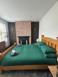 a bedroom with a large green bed with a fireplace at City Centre Chic in Bangor