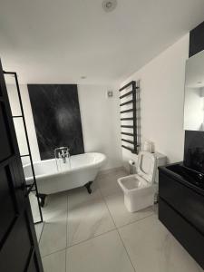 a bathroom with a tub and a toilet and a sink at City Centre Chic in Bangor