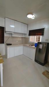 a kitchen with white cabinets and a black refrigerator at Danielle's Haven in Naga +4 photos