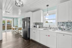 a kitchen with white cabinets and a black refrigerator at Newly Renovated 2 Bedroom Beach House Free Parking in Panama City Beach