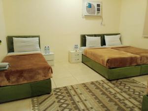 a bedroom with two beds and a rug at دار الرضا Dar Al Reda in Al Madinah